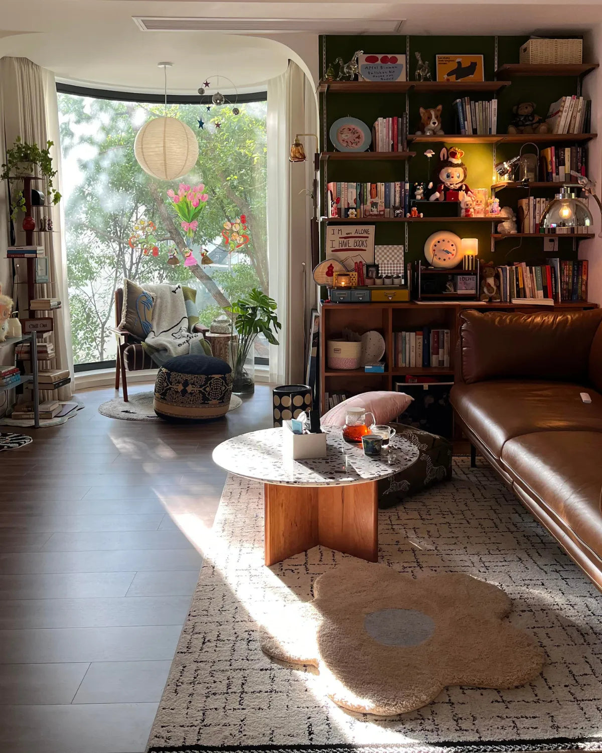 Housenfriends Maisie cream and pale blue daisy-shaped tufted rug near a coffee table in a library style living room lined with bookshelves.